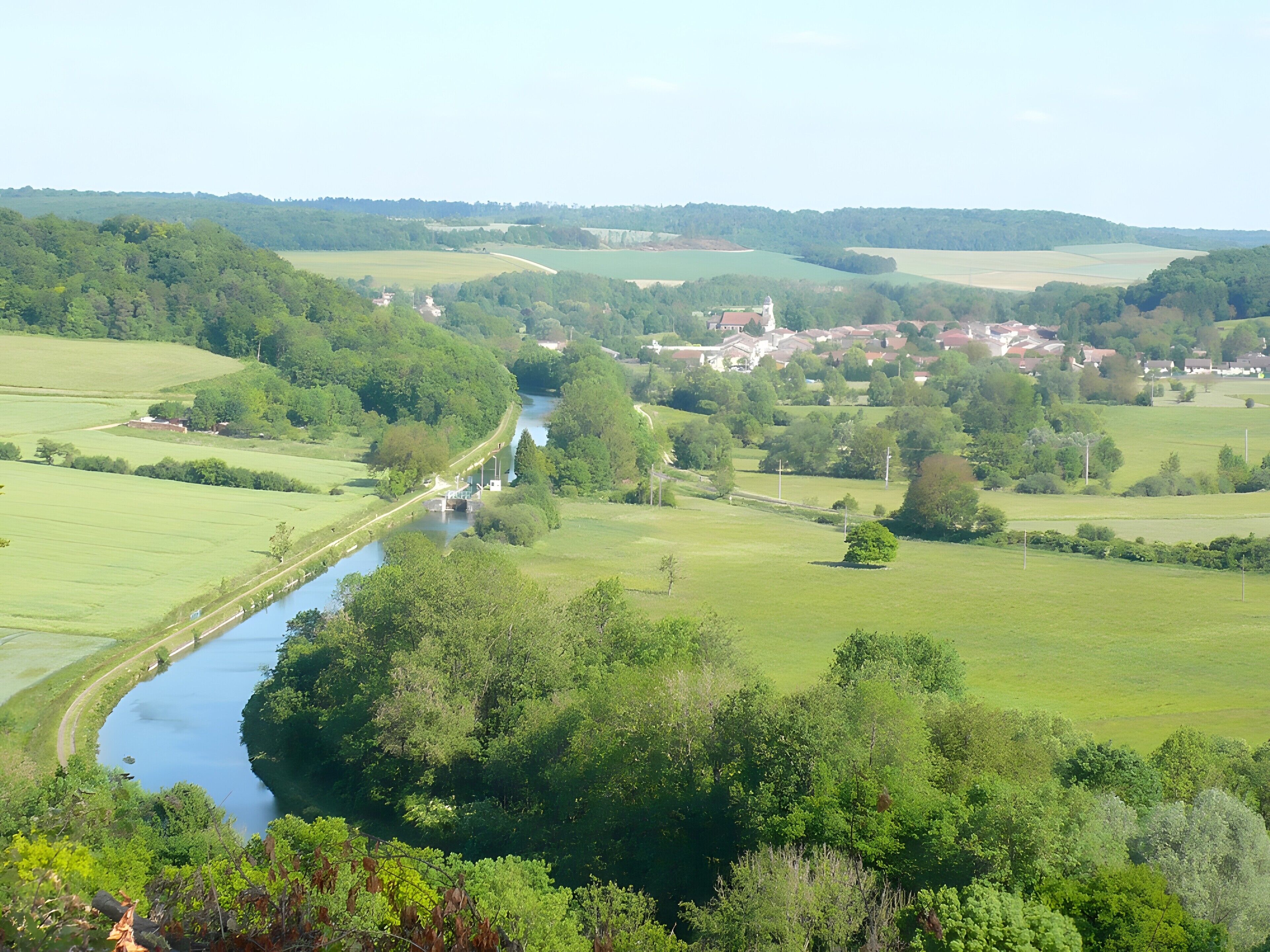Une rivière qui traverse un paysage rural, avec des champs et un petit village.