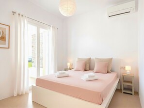 Ein Schlafzimmer mit einem großen Bett, zwei Nachttischen mit Lampen, einer Deckenleuchte und Blick durch das Fenster.