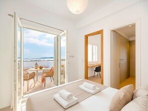 Ein Hotelzimmer mit Bett, einem Balkon mit Tisch und Stühlen sowie einem Schreibtisch mit Stuhl.