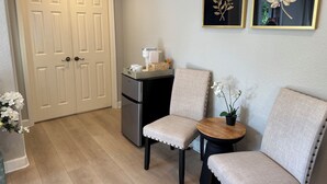 A compact kitchen with a refrigerator, a coffee maker, and a small table with chairs. There are two framed leaves on the wall. - Elegant Designer Suite: Serene Garden View & Private Entry (Escondido)