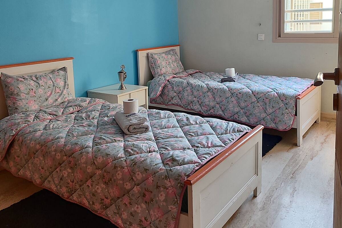 Un dormitorio con dos camas, una ventana y una lámpara en el techo.