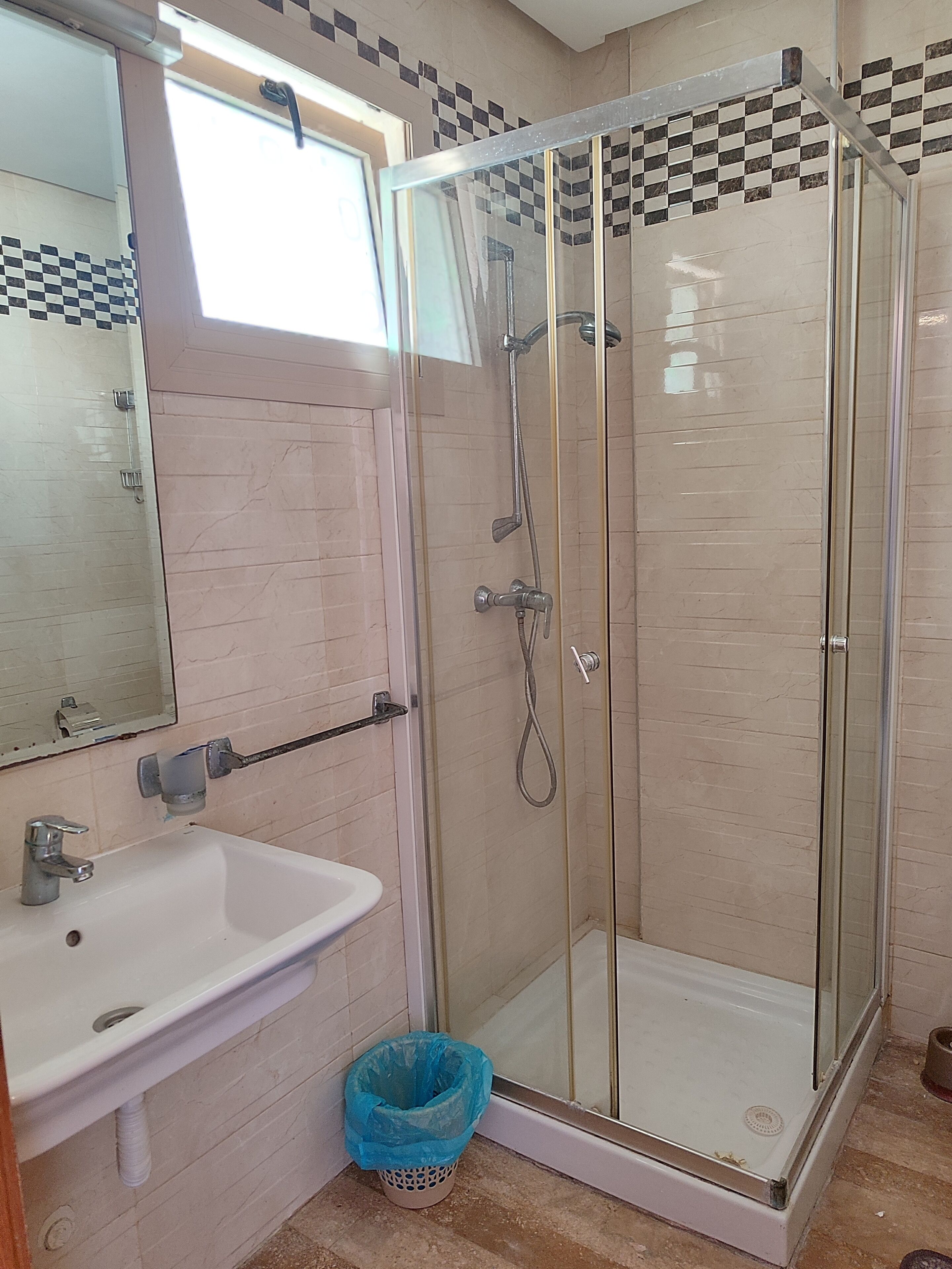 A bathroom with a glass-enclosed shower, a sink, and a mirror.