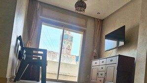 A spacious room with a large window, a flat-screen TV mounted on the wall, and a ceiling fan. - Melliber A  (Casablanca)