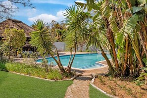 A pool surrounded by tropical plants and a thatched-roof structure. - Zinziluxe Guesthouse (Johannesburg)
