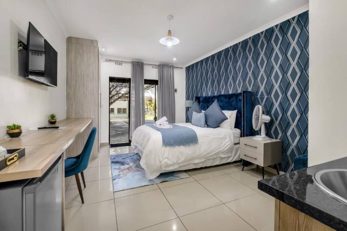 A modern hotel room with a bed, a desk, a TV, and a bathroom.