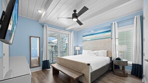 Ein Schlafzimmer mit Bett, einer Bank, einem Deckenventilator, einem Fernseher und Blick ins Freie.