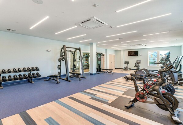 Un gimnasio con equipo de ejercicio, alfombra azul y suelo estampado.