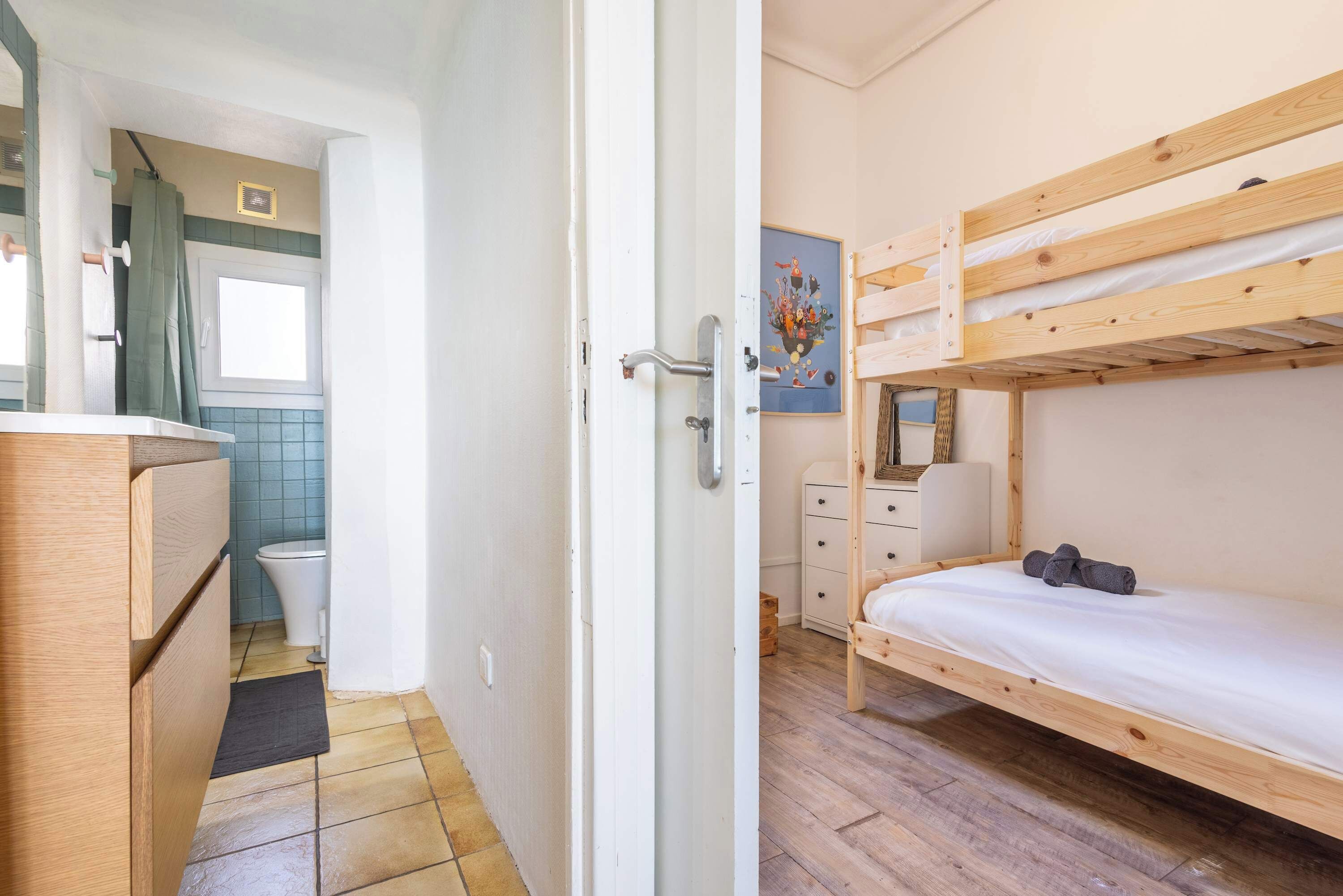Une pièce comprenant un lit superposé, un petit bureau avec une chaise, des toilettes et un espace douche.