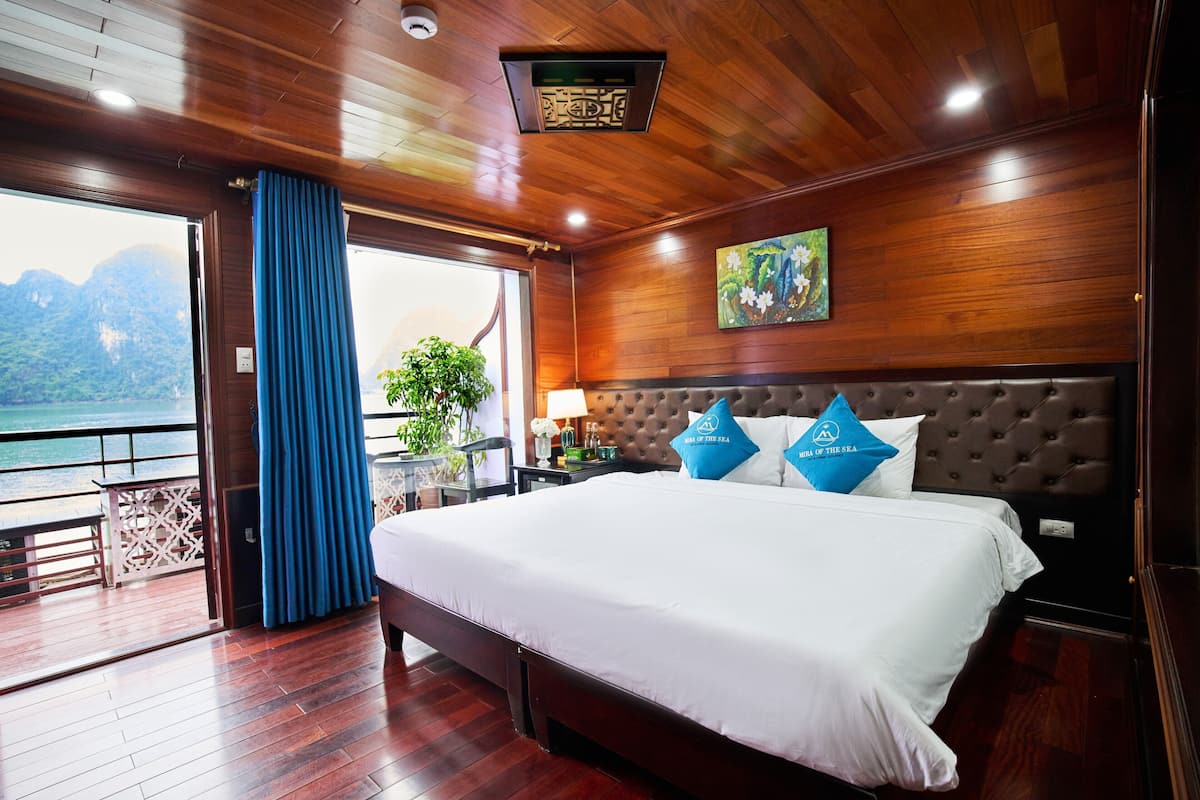 Una habitación con una cama grande, vista al mar y techo de madera.