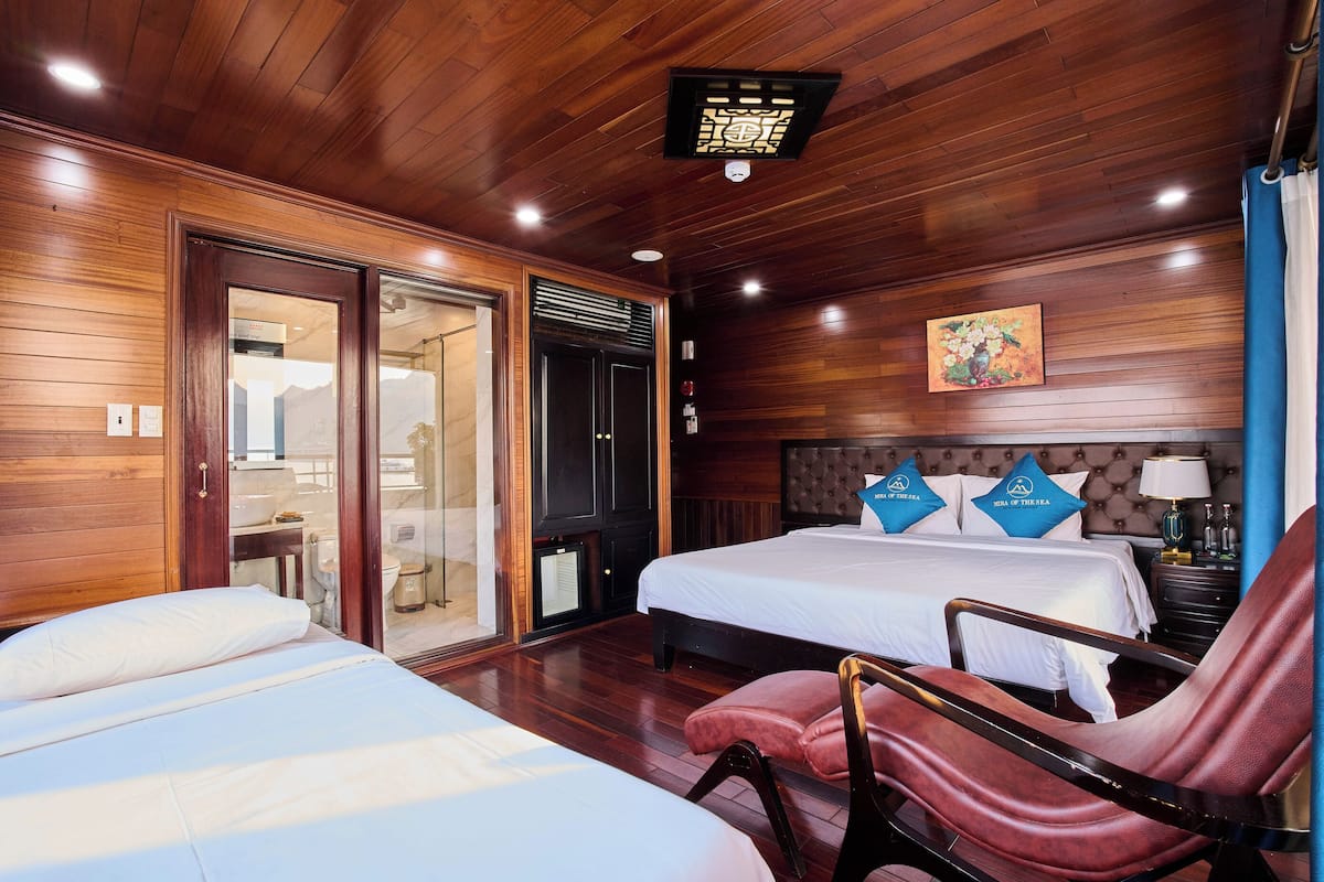 Habitación de hotel con dos camas, techo de madera, un cuadro y una mesita de noche con lámpara.