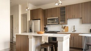 Eine moderne Küche mit Holzschränken, Edelstahlgeräten und einer zentralen Kochinsel mit Sitzgelegenheiten.