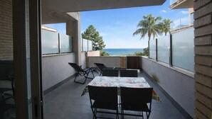 A balcony with a table and chairs, a view of the sea, and palm trees. - Apartment Panoramic B4 by Parc Mont-roig (Miami Playa)