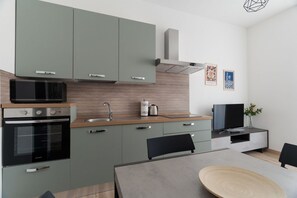 Una cucina moderna con microonde, forno e lavello. C'è un tavolo da pranzo con sedie e un televisore a schermo piatto.