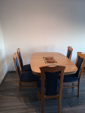 A rectangular wooden dining table with a metal grid in the center, surrounded by four chairs with dark blue upholstery.