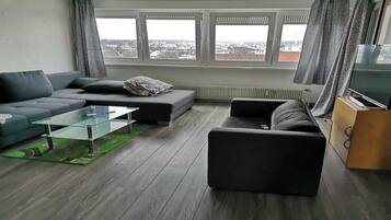 Een moderne woonkamer met een bank, een glazen salontafel en een tv-meubel.