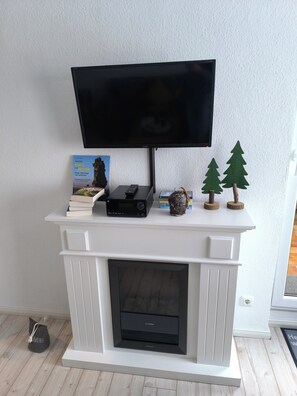 Ein weißer Kamin mit einem flachbildfernseher darüber.