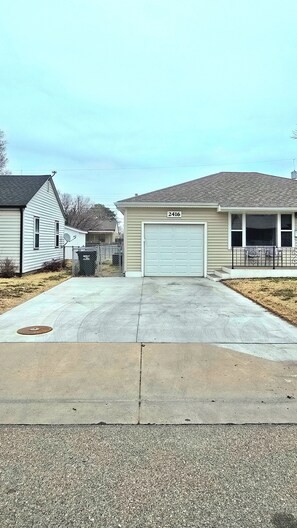 Une rue résidentielle bordée de maisons, avec un garage et un trottoir.