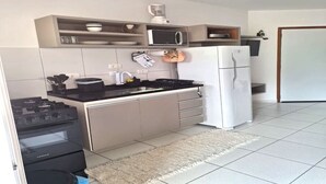 Una cocina moderna con estufa a gas, microondas y refrigerador blanco.