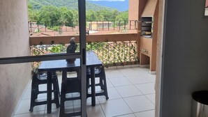 Un balcón con mesa y sillas, vista a un paisaje montañoso y suelo de baldosas.