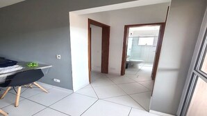 Una habitación moderna con una mesa de comedor, una planta pequeña y vista a un baño por una puerta abierta.