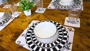 Une table dressée avec de l’assiette, des bols et des verres aux motifs noir et blanc, et une petite plante posée sur la table.