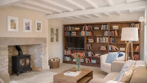 Un salon chaleureux avec une cheminée, des étagères à livres, un canapé et une table basse.