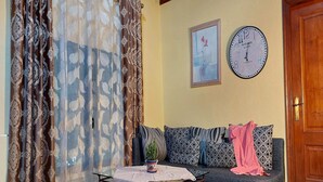 A living room with a sofa, a table with a plant, a clock, and a door. - Detached Terrace Cottage for Adults Only (Icod de los Vinos)