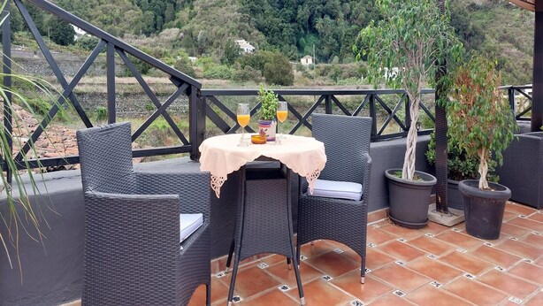 An outdoor patio with wicker furniture, a table with a tablecloth, and potted plants. - Detached Terrace Cottage for Adults Only (Icod de los Vinos)