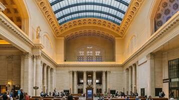 Eine großzügige Lobby mit hohen Decken und Oberlicht, mit Marmorsäulen und einer zentralen Treppe.