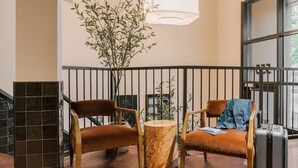 A modern lobby with two leather chairs, a marble table, and a large window.