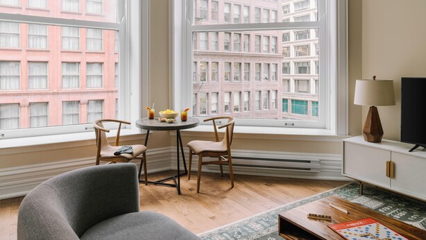 A room with a large window, a round table with chairs, a television, and a lamp. - LIVN Millennium Park Downtown Chicago Superior 1BR (Chicago)