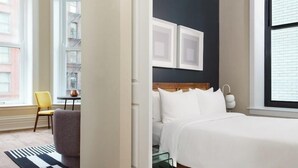 A hotel room with a bed, a chair, a table, and a window with a view of buildings. - LIVN Millennium Park Downtown Chicago Superior 1BR (Chicago)