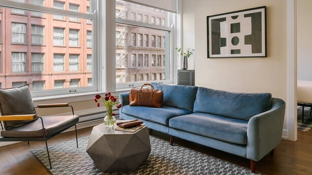 A modern living room with a blue sofa, a leather armchair, and a geometric coffee table.