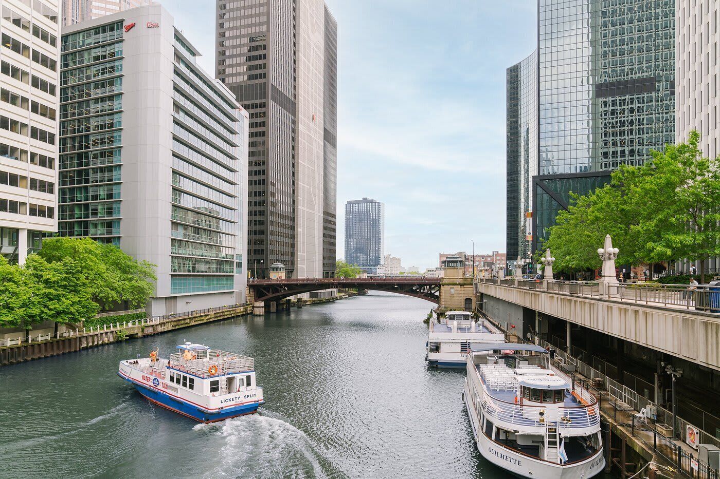 A river with boats, a bridge, and modern buildings.
