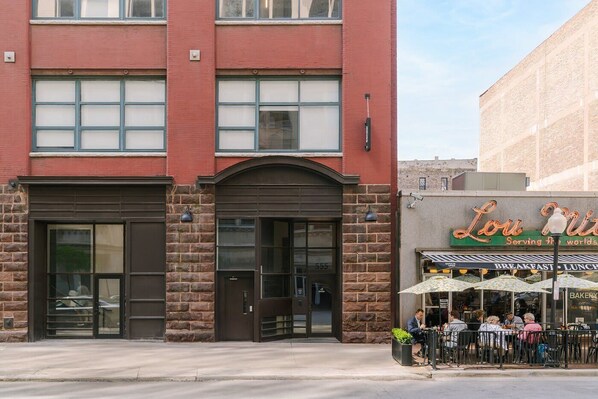 A building with a red facade, a stone entrance, and a storefront with outdoor seating.