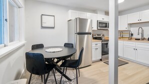 A modern kitchen with white cabinets, a stainless steel refrigerator, a microwave, and a sink.