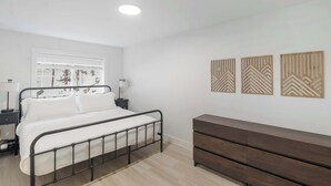 A bedroom with a bed, bedside tables, a dresser, and wall art.
