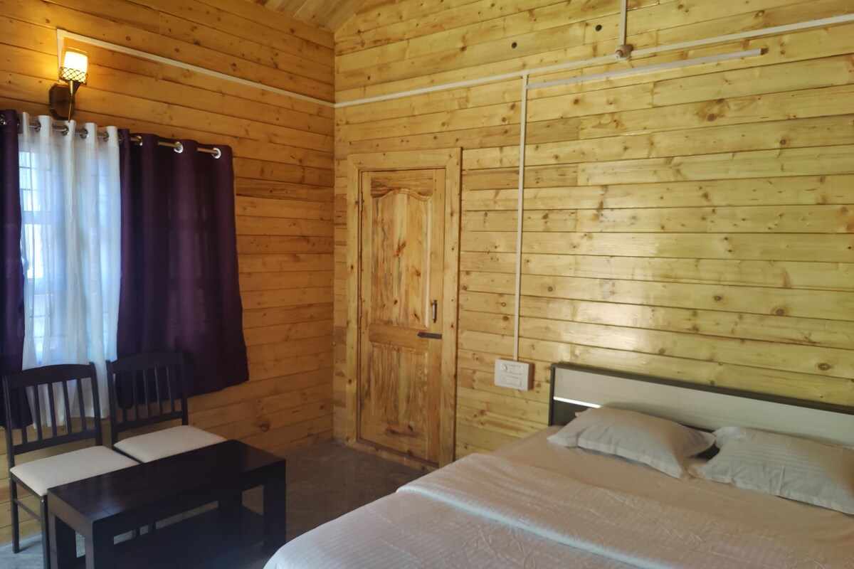 Una habitación de madera con una cama, un banco y una puerta.