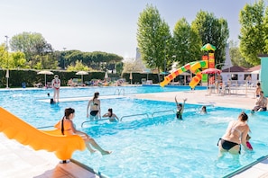 Een zwembad met een glijbaan, parasols en mensen die zwemmen en ontspannen.