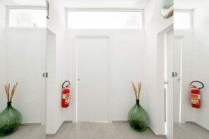 A hallway with white doors, fire extinguishers, and green vases. - Heart in Home - One Bedroom Apartment, Sleeps 2 (Monopoli)