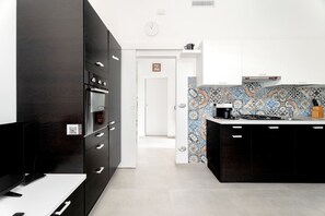 A modern kitchen with black cabinetry, a tiled backsplash, and a white countertop. - Heart in Home - One Bedroom Apartment, Sleeps 2 (Monopoli)