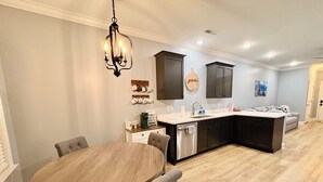 A modern kitchen with a round wooden table, dark cabinets, and a hanging light fixture. - Urban Oasis 456 - Close to everything in Cleveland! (Cleveland)