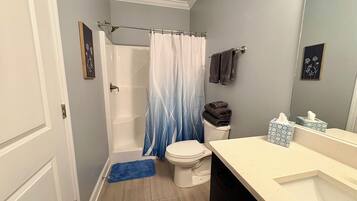 A bathroom with a shower, toilet, and sink.