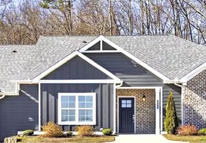 A residential house with a dark gray exterior, a white-framed garage door, and a brick section on the right side. - Urban Oasis 456 - Close to everything in Cleveland! (Cleveland)