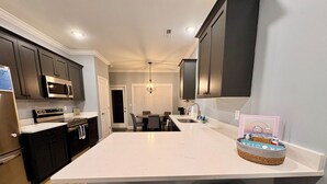 A modern kitchen with dark cabinets, a white countertop, and a central island. There are two wicker chairs in front of the island. - Urban Oasis 456 - Close to everything in Cleveland! (Cleveland)