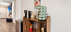 Eine Kaffeestation mit Kaffeemaschine, Espresso-Kapseln und einem Poster einer Kaffeetasse.