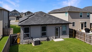 Il s’agit d’une propriété résidentielle dotée d’une pelouse bien entretenue, d’une maison de plain-pied avec un toit foncé et d’un barbecue extérieur bien visible.