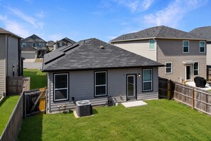 Ein Wohnhaus mit gepflegtem Rasen, ein eingeschossiges Haus mit dunklem Dach und ein sichtbarer Grill im Freien.