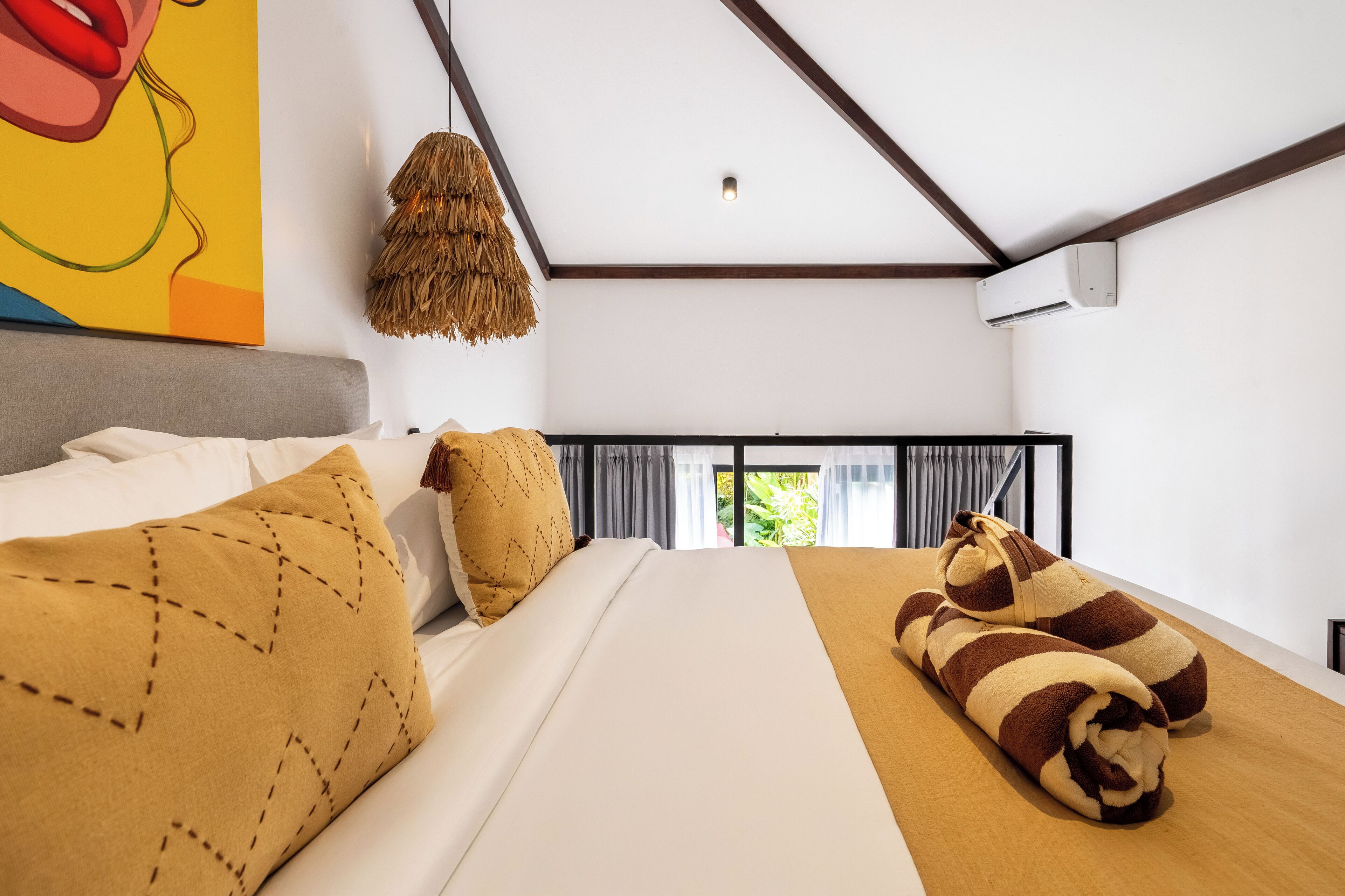 Una habitación de hotel moderna con una cama grande, vista a zonas verdes y un ventilador de techo.