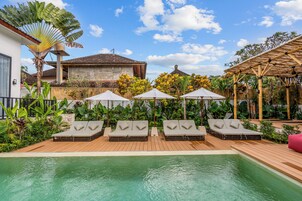 Una piscina al aire libre, sombrillas, sillones reclinables de piscina